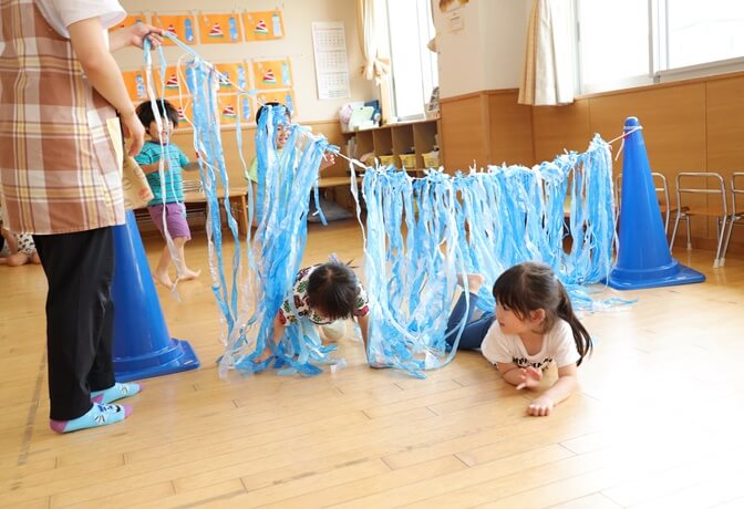 室内で遊ぶ子供たちと保育士